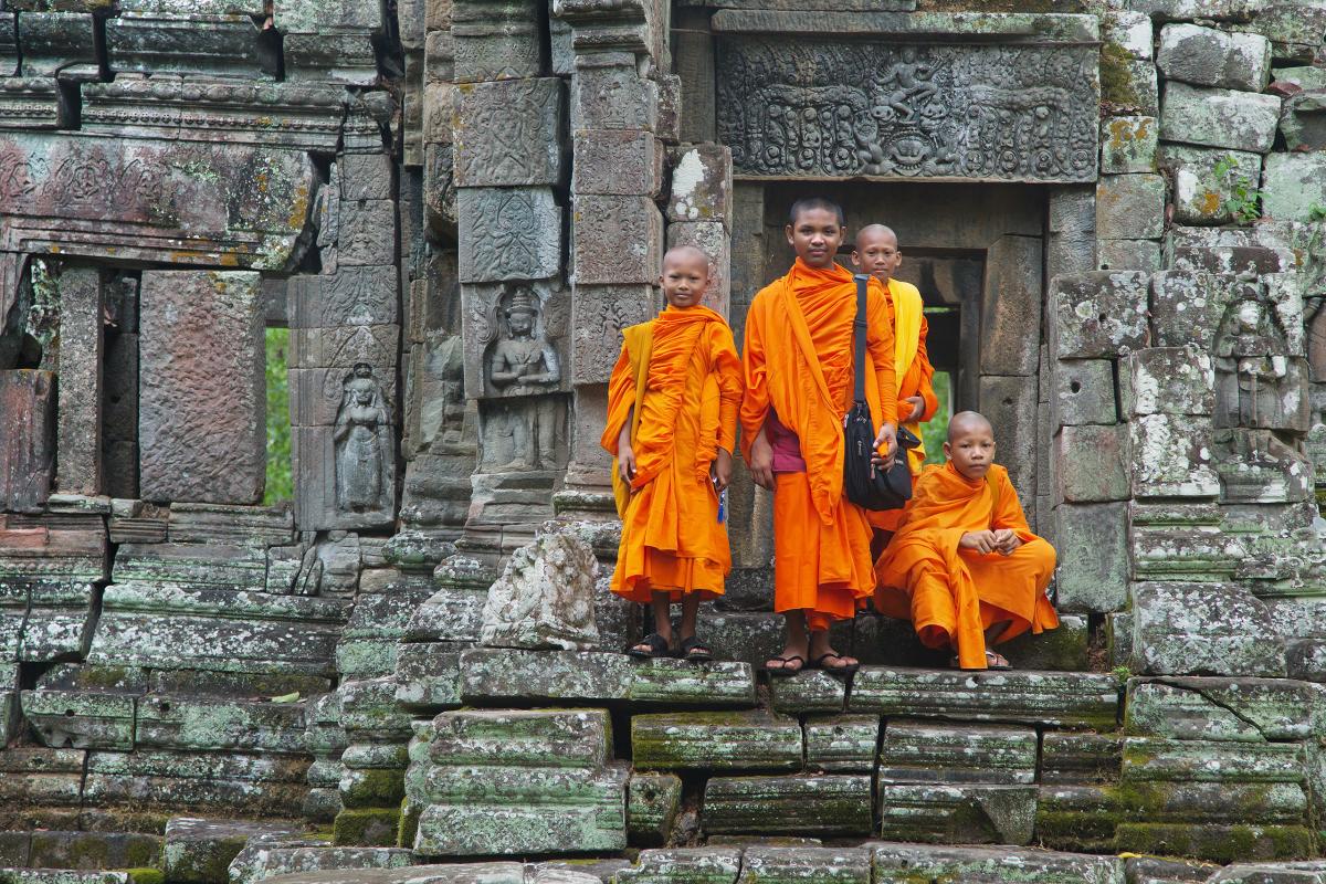 Young buddhist monks stand in front of their temple