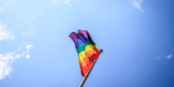 Pride flag waves in a blue sky